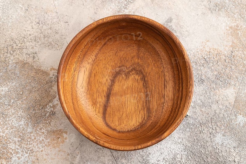 Empty brown wooden bowl on brown concrete background. Top view, copy space, flat lay