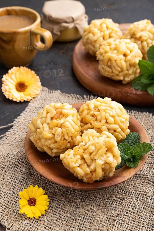 Traditional Tatar candy chak-chak made of dough and honey with cup of coffee on a black concrete background and linen textile. Side view, close up