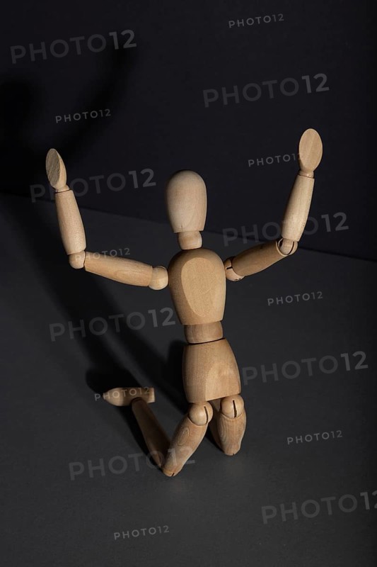 Wooden mannequin in imploration, praying position on gray background. religion, despair concept. copy space, hard light