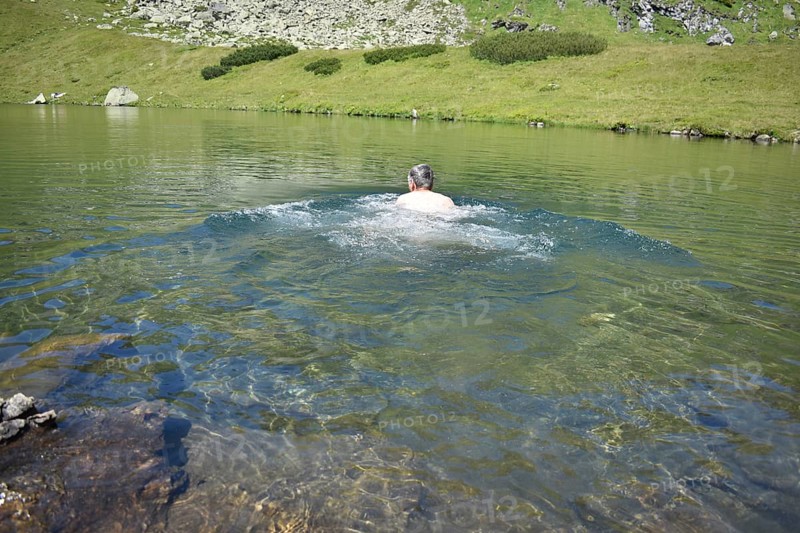 Hiker swimming in the ice-cold mountain lake Mittlerer Kaltenbachsee, Sölktäler Nature Park, Niedere Tauern, Styria, Austria, Europe