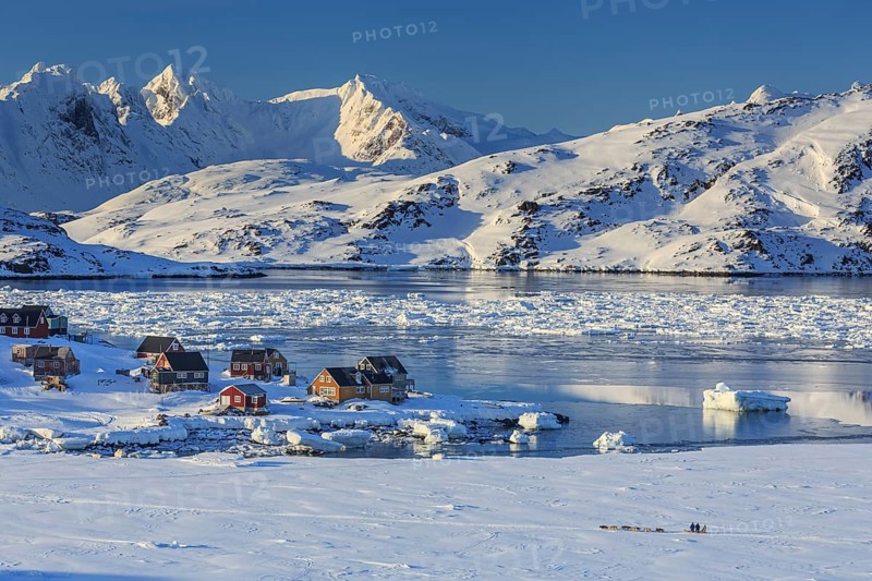 Inuit settlement, houses on fjord with icebergs in front of snowy mountains, winter, sunny, Kulusuk, East Greenland, Greenland, North America