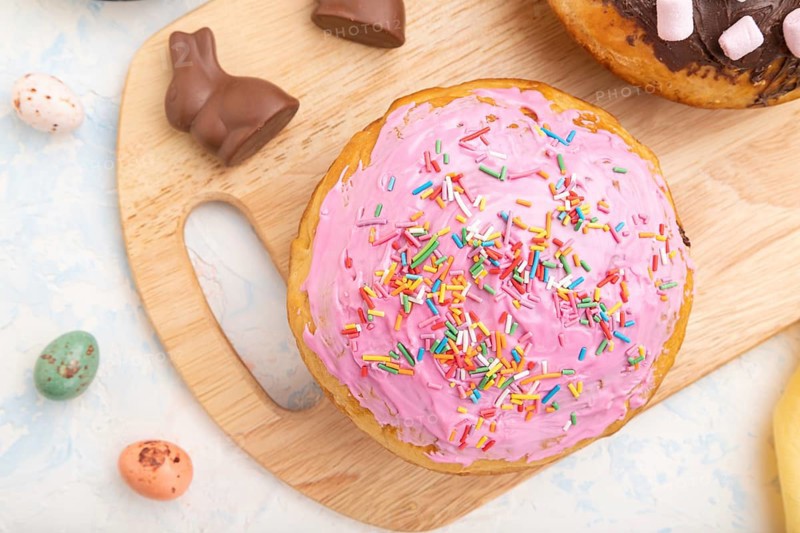 Homemade glazed and decorated easter pies with chocolate eggs and rabbits on a white concrete background and yellow textile. top view, flat lay, close up