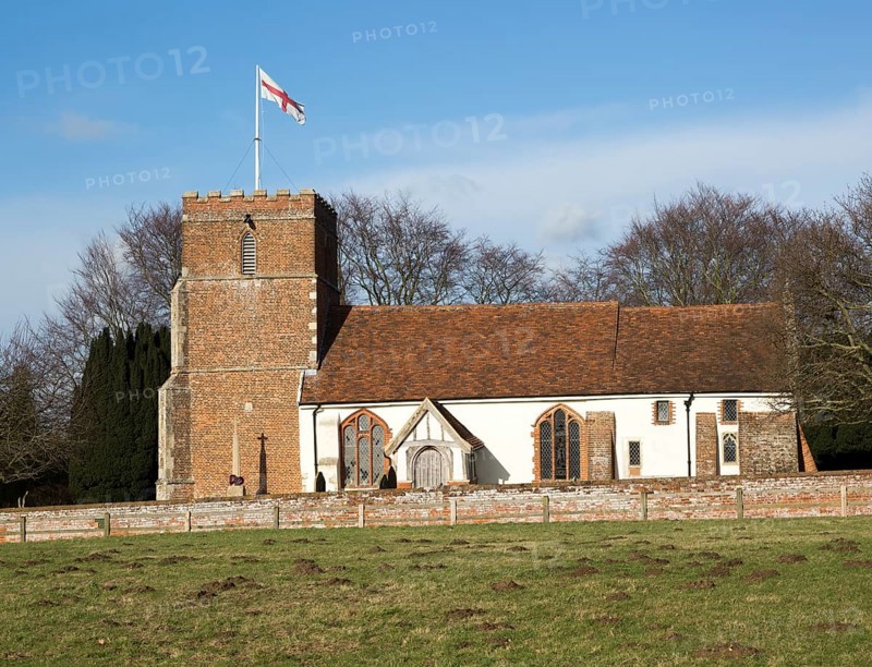 Red cross of flag of St George flying from tower of village Saint Peter church, Levington, Suffolk, England, UK