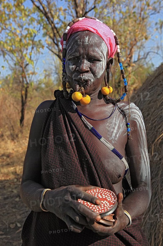 South Ethiopia, in Maco National Park, Mursi tribe, plate lip woman, Mursi woman with naked upper body and painted skin and earrings, holding plates for lip jewellery, Ethiopia, Africa
