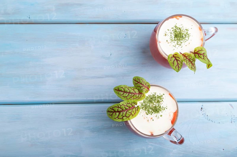 Tomato juice with sorrel and sour cream in glass on blue wooden background. Healthy drink concept. Top view, flat lay, copy space