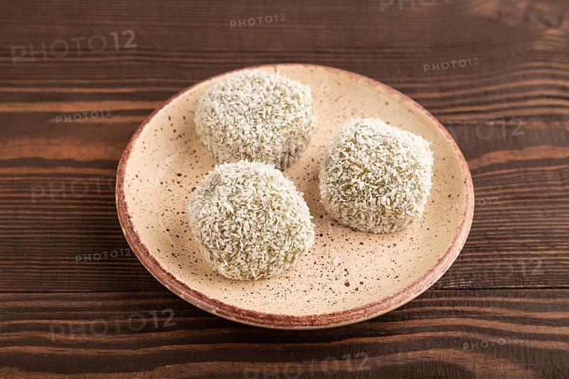 Japanese rice sweet buns mochi filled with pandan and coconut jam on brown wooden background. side view, close up