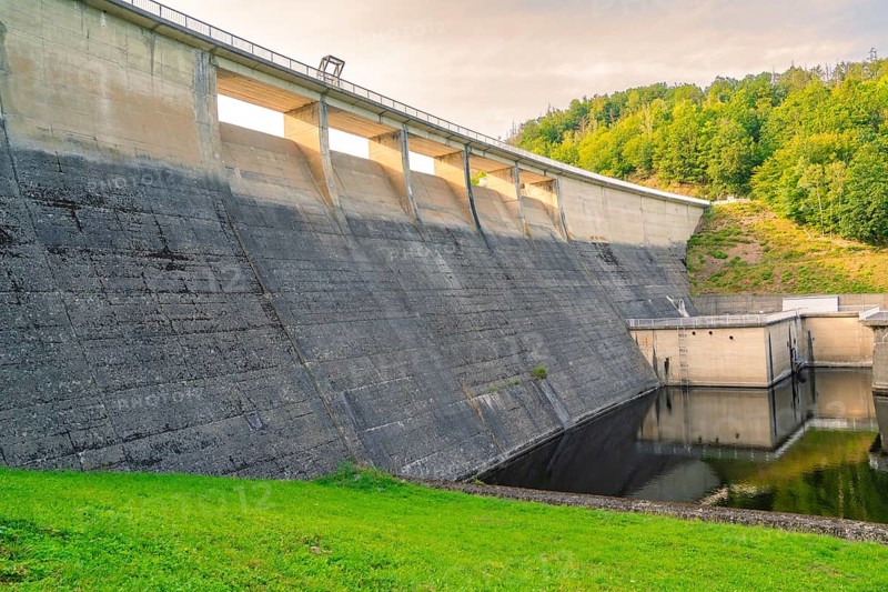 An imposing concrete dam with flowing water, embedded in a green hilly landscape, Rappbodetalsperre, Harz, Germany, Europe
