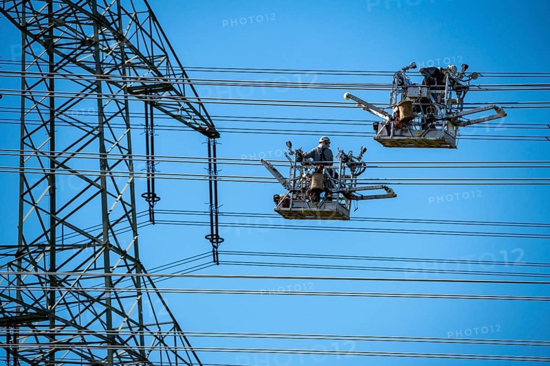 Construction of a new line route, 380 KV extra-high-voltage line between Osterath and Gohr, near Neuss, fitters in line trolleys, on the conductor cables, installing field spacers at great heights, North Rhine-Westphalia, Germany, Europe