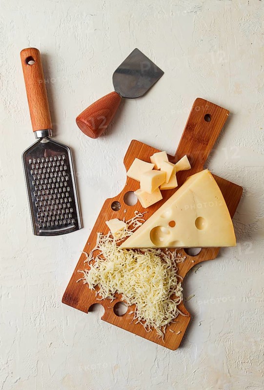 Grated cheese, Maasdam, on a cutting board, grater and cheese knife, close-up, no people