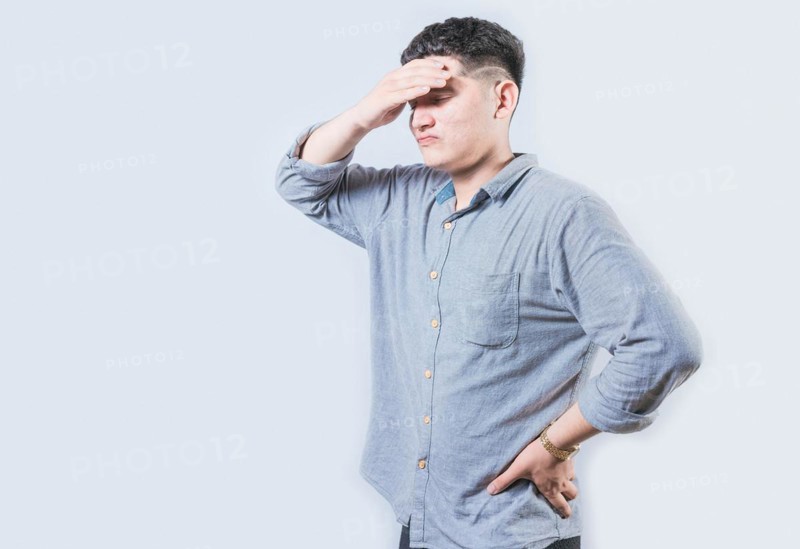 Tired man holding his head isolated. Worried young man holding his forehead isolated
