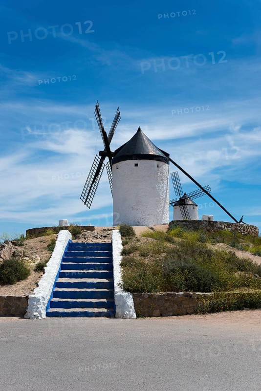 White windmill against a blue sky, flanked by a blue and white stone staircase, surrounded by nature, Consuegra, Toledo, Castilla-La Mancha, Route of Don Quixote, Spain, Europe