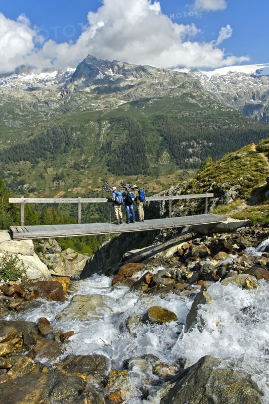 Hikers cross a narrow bridge over the Nästbach torrent on the way to the Bietschhorn hut, near Blatten, Lötschental, Valais, Switzerland, Europe
