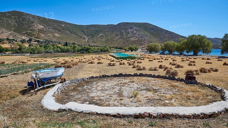 Rural scene with a field, a boat, mountains and some scattered trees, bales of straw, Old threshing floor, Psili Ammos Srand, Patmos, Dodecanese, Greek Islands, Greece, Europe