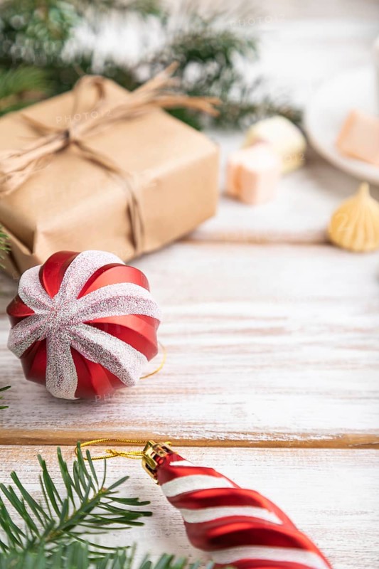 Christmas or New Year composition. Decorations, box, balls, cinnamon, fir and spruce branches, cup of coffee, on a white wooden background. Side view, copy space, selective focus