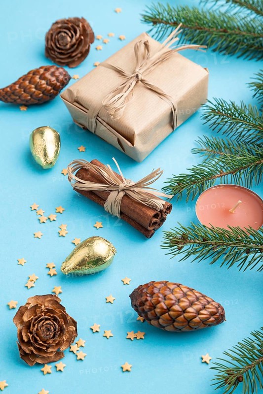 Christmas or New Year composition. Decorations, box, cinnamon, cones, fir and spruce branches, on a blue paper background. Side view, close up