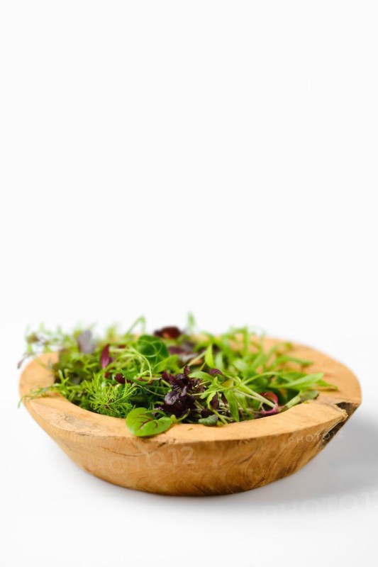 Wooden bowl with different microgreens on white background