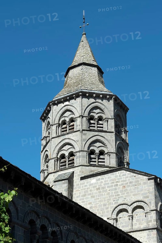 Orcival. Bell tower of the Notre-Dame d'Orcival basilica showcasing Romanesque architecture under a clear blue sky, Puy de Dome, Auvergne-Rhone-Alpes, France, Europe