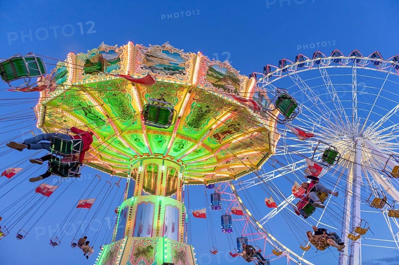 Illuminated chain carousel and Ferris wheel at night with cheerful people, funfair, wave flight, Cannstadter Volksfest, Stuttgart-Bad Cannstsdt, Baden-Württemberg