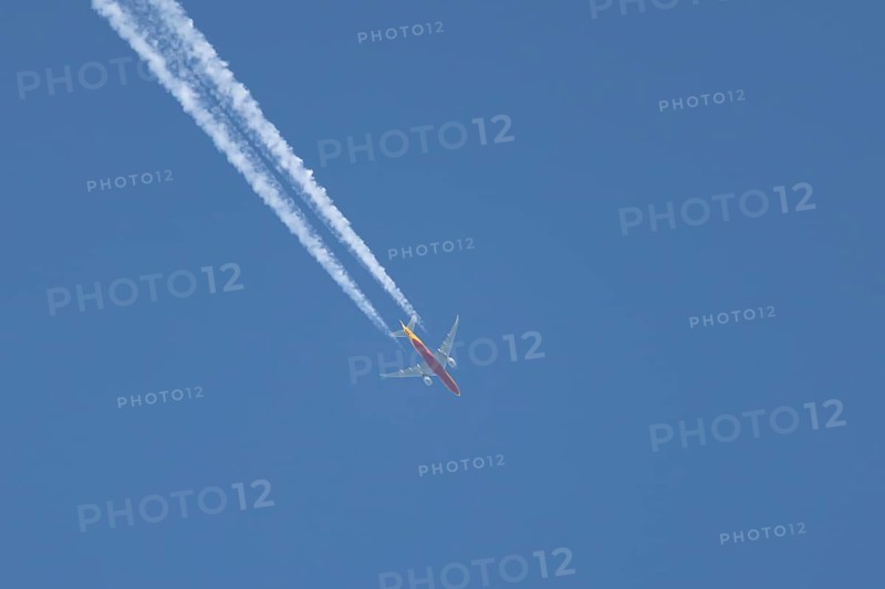 Boeing 767 jet cargo aircraft of DHL flying in a blue sky with a vapor trail or contrail behind, England, United Kingdom, Europe