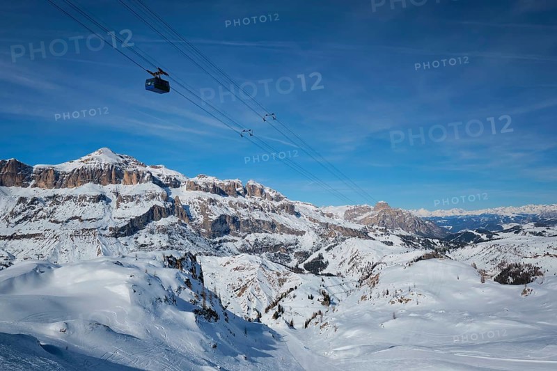 View of a ski resort piste with people skiing in Dolomites in Italy with cable car ski lift. Ski area Arabba. Arabba, Italy, Europe