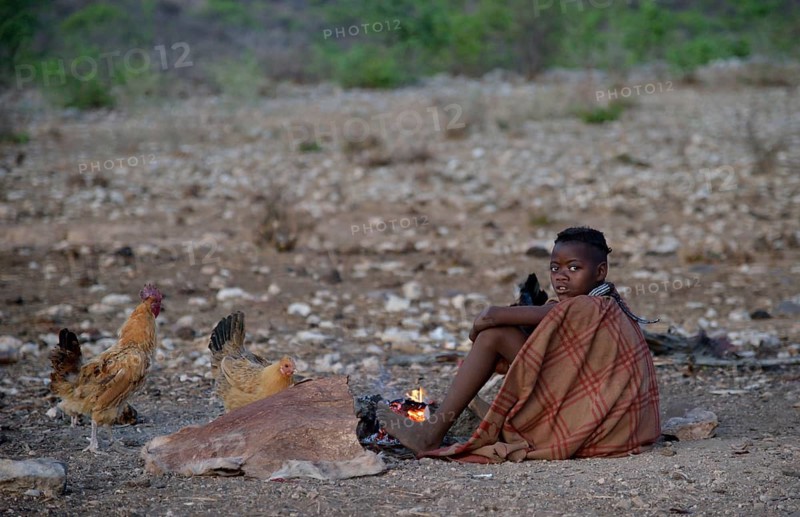 Young shepherdess from the Himba people sitting by a campfire, Ombombo, Kaokoland, Kunene, Namibia, Africa