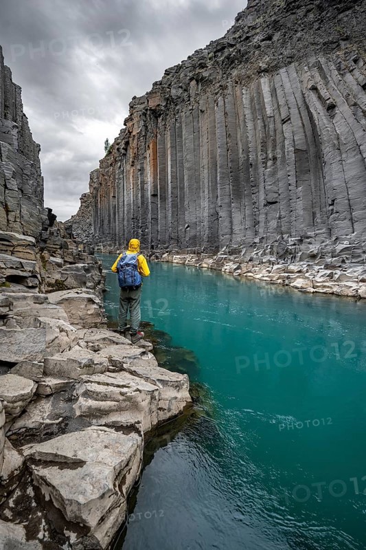 Tourist standing by the river in Stuðlagil Canyon, turquoise blue river between basalt columns, Egilsstadir, Iceland, Europe