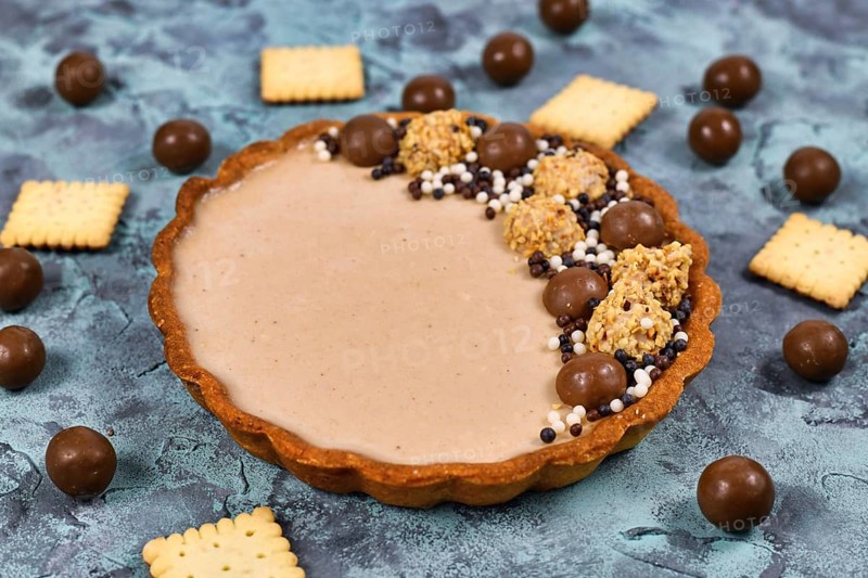 Sweet tart with cheesecake milk chocolate cream filling topped with pralines and chocolate sprinkles