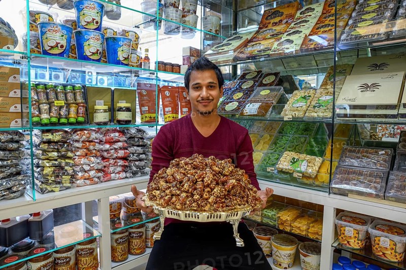 Seller with a bowl of dates, Date market, Abu Dhabi City, Emirate of Abu Dhabi, United Arab Emirates, Asia