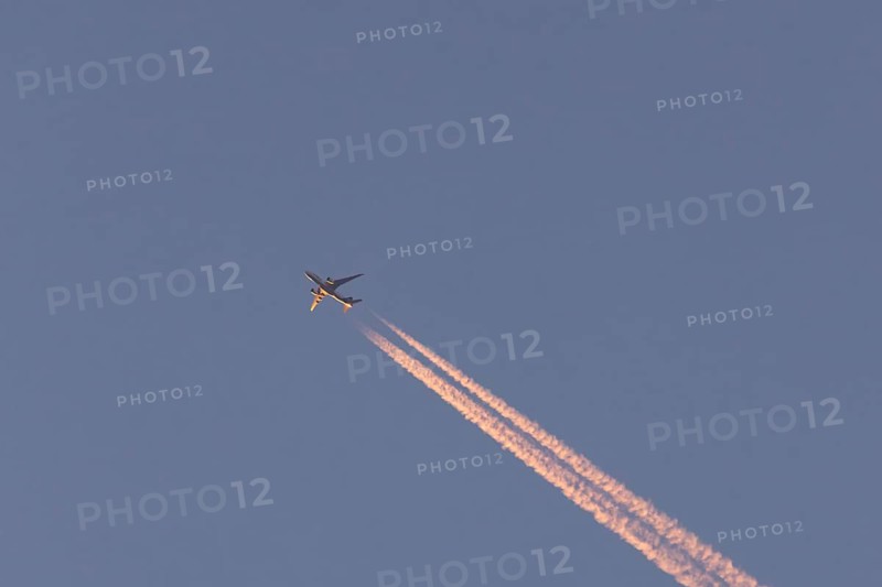 Boeing 767 jet cargo aircraft of FedEx flying in a blue sky with vapor trails or contrails behind, England, United Kingdom, Europe