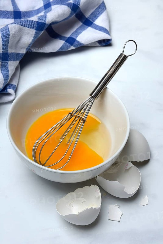 Whipped egg in shell with whisk, egg shells