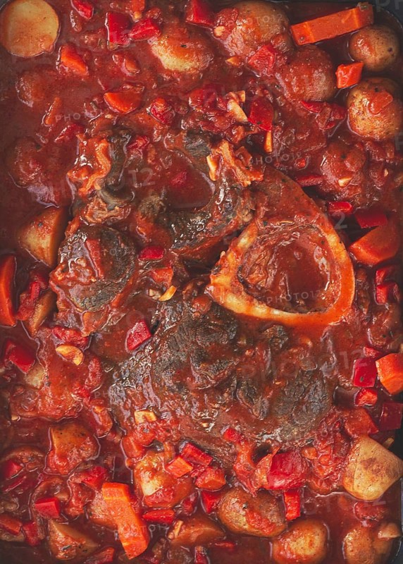 Ossobuco stew with vegetables, knuckle on the bone with new potatoes, in tomato sauce, homemade, top view, no people