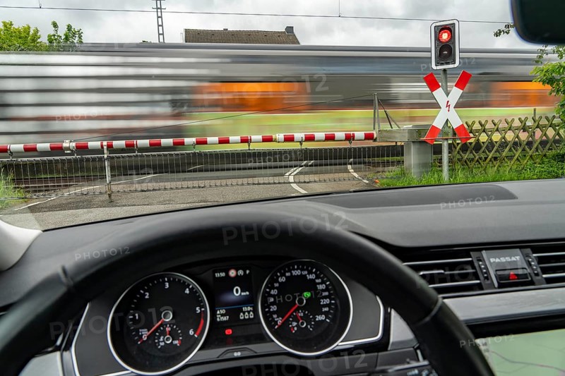Car waiting at a level crossing, closed barriers, red warning light, traffic light and St Andrew's cross, RRX, Rhein-Ruhr-Express, National Express passes by, near Geilenkirchen North Rhine-Westphalia, Germany, Europe