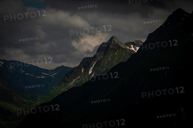Grassy summit with remnants of snow and dramatic clouds, Lech, Lechquellengebirge, Vorarlberg, Austria, Europe