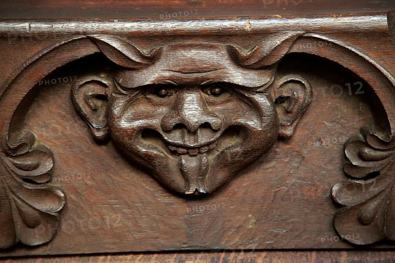 Wooden carved devil face in bench seat, Ufford church, Suffolk, England, UK