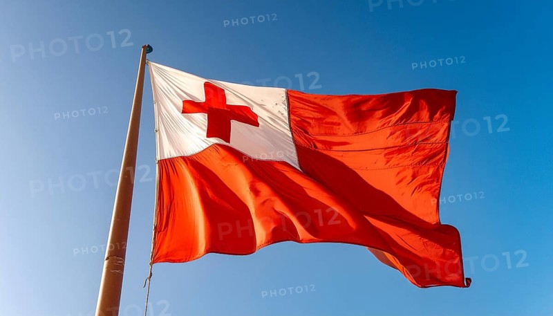 The flag of Tonga, Pacific island state, flutters in the wind, isolated against a blue sky