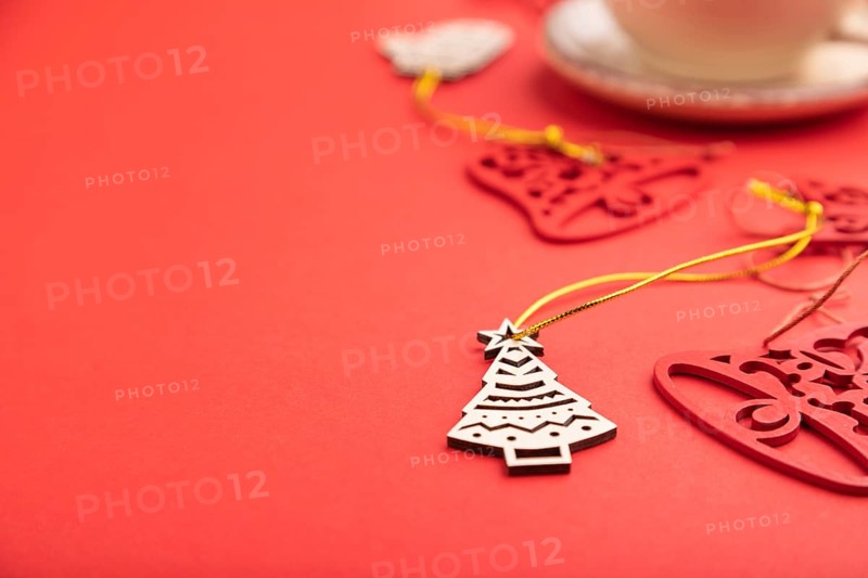 Christmas or New Year composition. Decorations, fir and spruce branches, cup of coffee, on a red paper background. Side view, selective focus, copy space