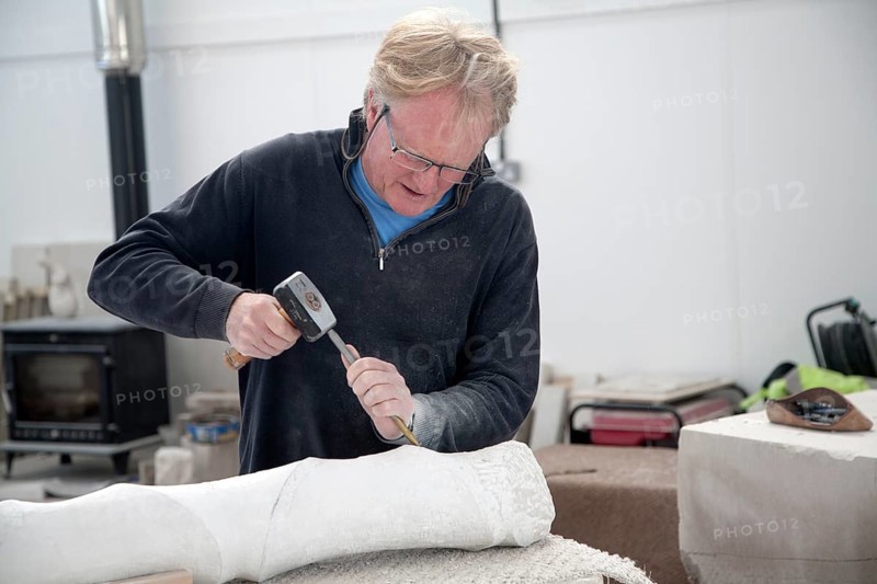 Sculptor working on local Portland stone in a community studio space on the Isle of Portland, Dorset, England, UK