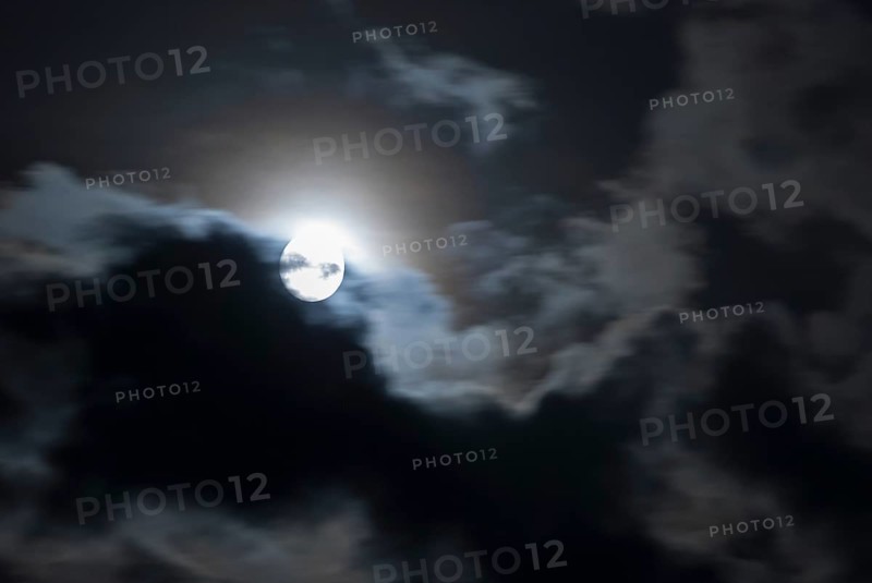The full moon shines brightly in a cloudy, stormy, black sky and has a halo (corona), fairytale-like, mystical night shot, dark, somewhat creepy mood, ghostly, symbolic image for fear, nightmare, horror, fantasy, motion blur, wiping effect, Mecklenburg-Western Pomerania, Germany, Europe