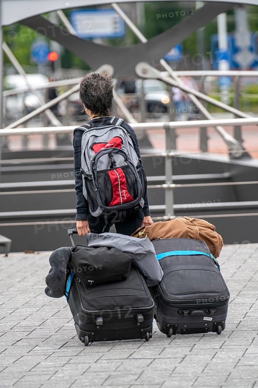 Travellers on their way to a river cruise ship at the quay of the Ij, transporting their luggage, wheeled suitcases, from the central station to the ship, Amsterdam, Netherlands