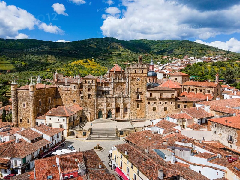 Aerial view of an old monastery with red roofs and surrounding hills under a blue sky in Spain. The architecture is historical and medieval, aerial view, pilgrimage church and monastery, Real Monasterio de Nuestra Señora de Guadalupe, Guadalupe, Cáceres province, Caceres, Extremadura, Spain, Europe