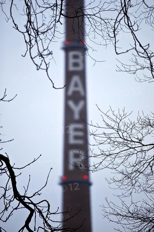 Bayer lettering on a chimney behind bare branches, Bayer AG, agrochemical and pharmaceutical company, Leverkusen, North Rhine-Westphalia, Germany, Europe