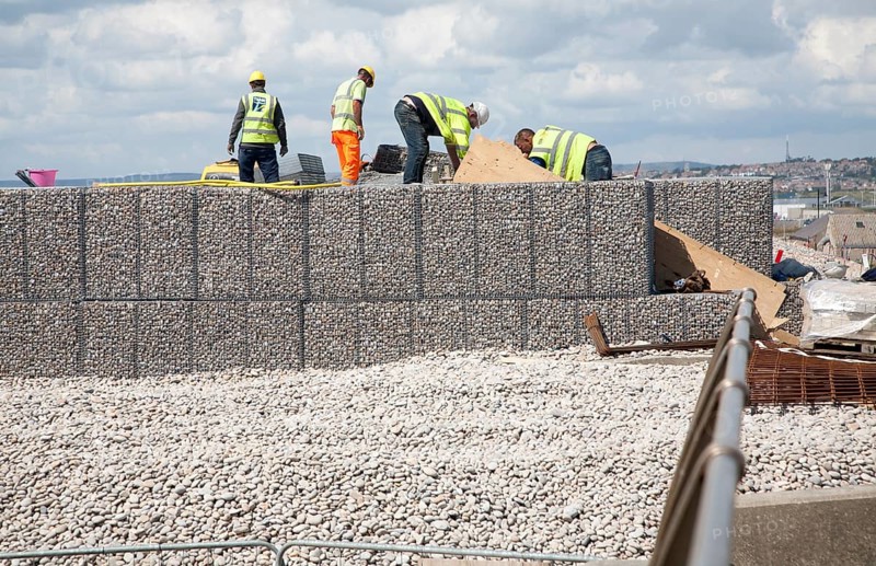 Repair work on steel mesh cages known as gabions which provide coastal defence at Chiswell, Isle of Portland, Dorset, England, UK
