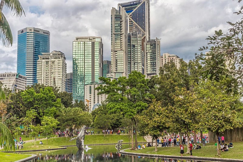 The city park with a small lake with buildings on background