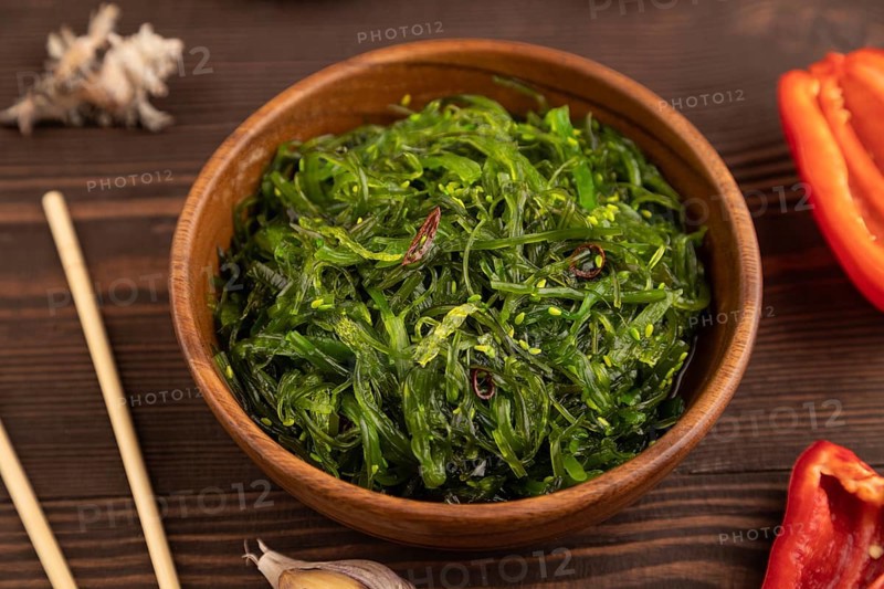 Chuka seaweed salad in wooden bowl on brown wooden background. Side view, close up, selective focus