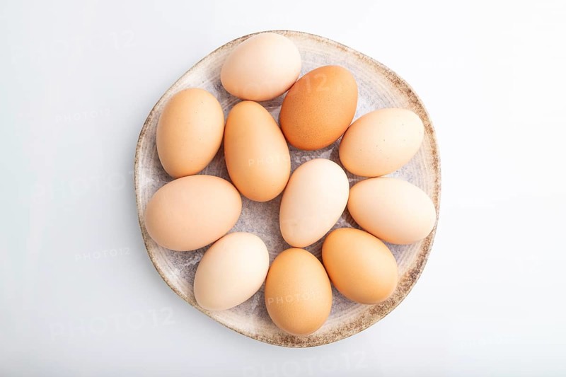 Pile of colored chicken eggs on plate isolated on white background. top view, flat lay, close up