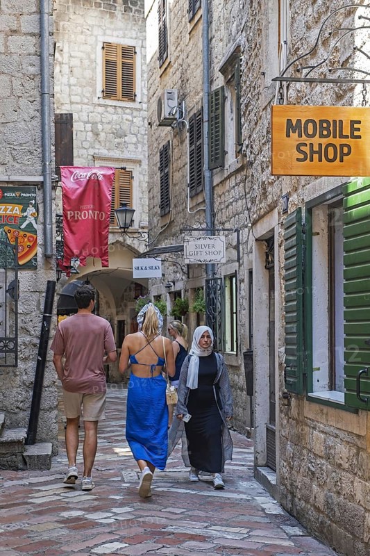 Western tourists and Muslim woman, muslima shopping in narrow alley in the Venetian Old Town centre of the city Kotor, southwestern Montenegro