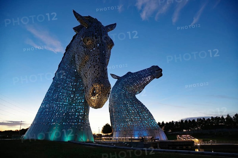 Two giant illuminated horse sculptures called Kelpies rise from the water at dusk, Forth and Clyde Canal, Falkirk, Scotland, United Kingdom, Europe