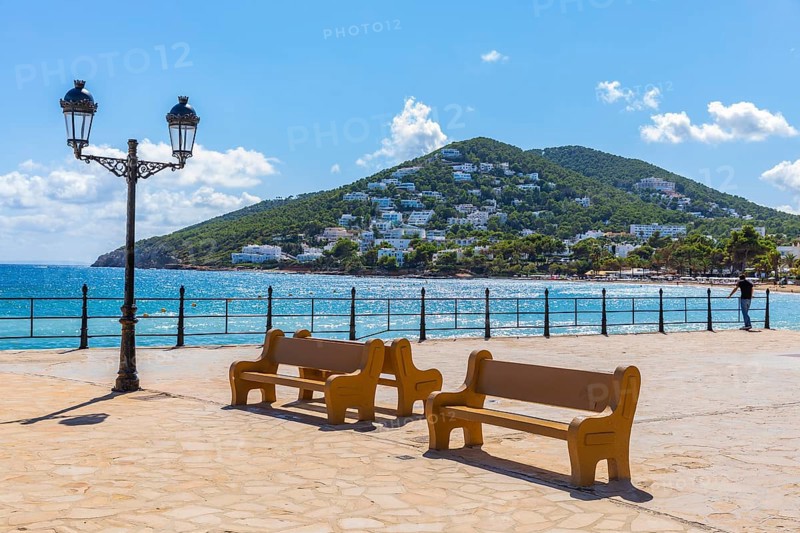 Large square at the harbour of Santa Eularia des Rui with lantern and benches, behind the peninsula La Siesta with holiday homes, Ibiza, Balearic Islands, Mediterranean Sea, Spain, Europe