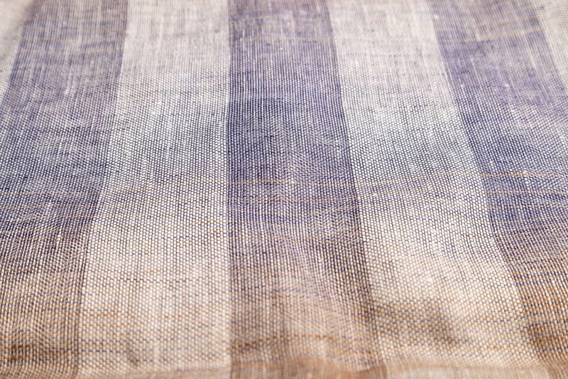 Fragment of smooth brown and violet linen tissue. Side view, natural textile background and texture