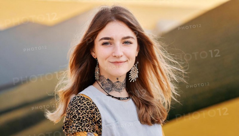 Smiling woman with tattoos and leopard print clothes in front of a dynamic yellow wall, AI generated, AI generated